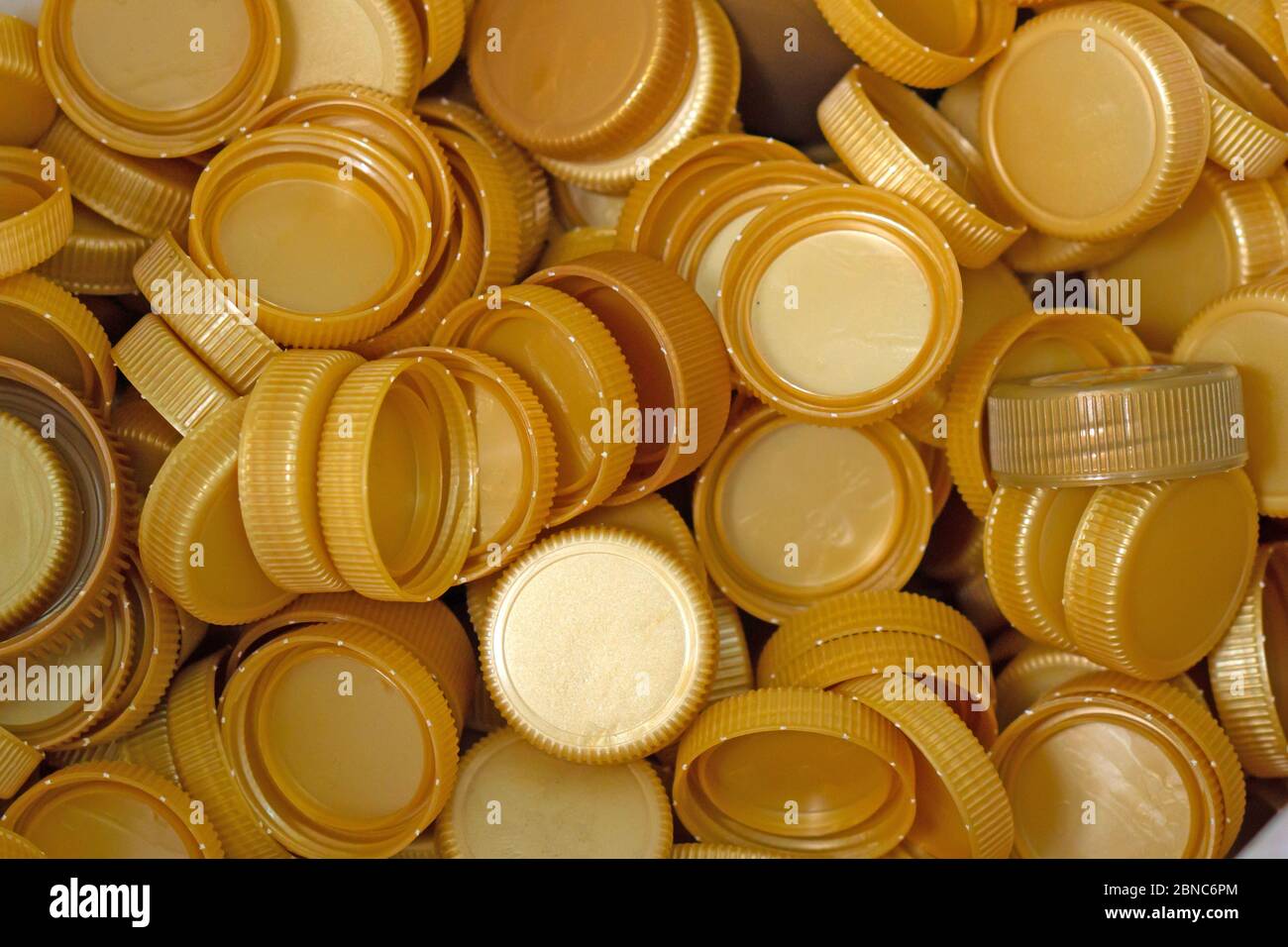 The gold plastic lid that is left over from the bottles are collected to be recycled into other items for reuse. Stock Photo