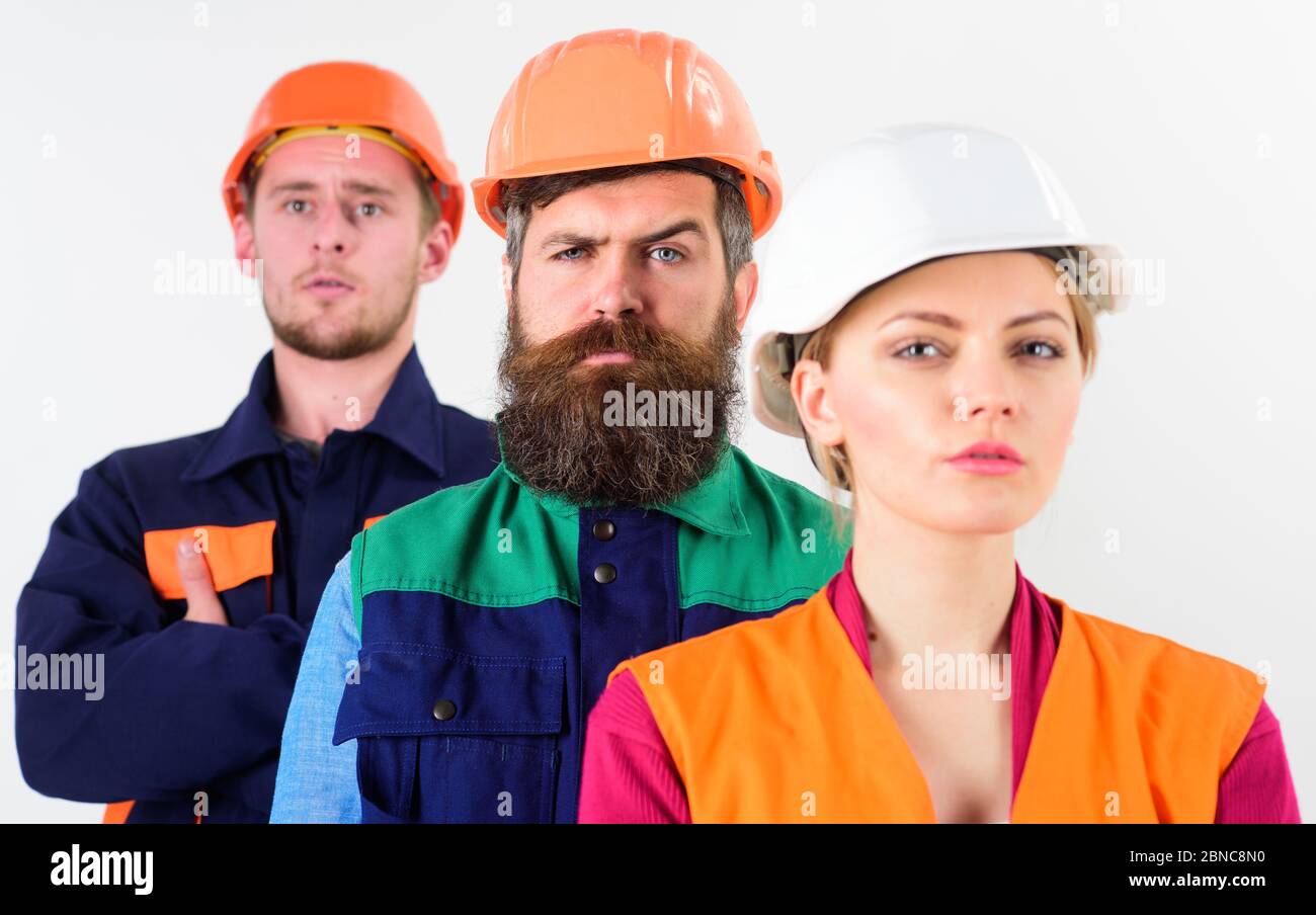 Serious team of three constructor workers in hard hats standing with ...