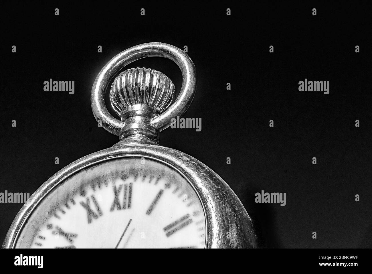 Greyscale closeup shot of a vintage pocket watch with a black