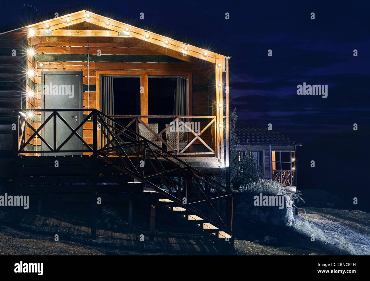 Modern wooden house decorated with yellow glowing bulbs at the mountain resort Stock Photo