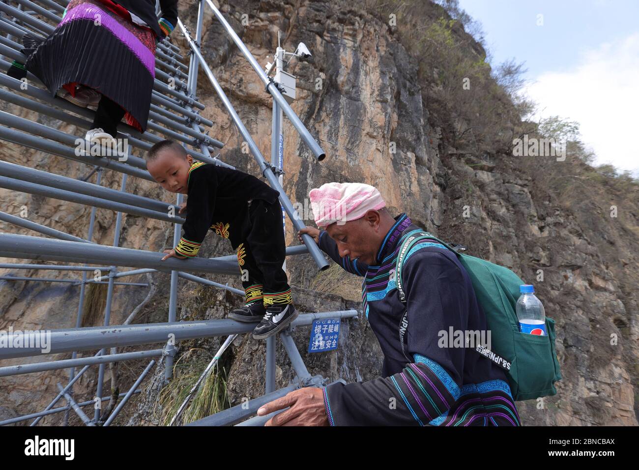 Zhaojue, China's Sichuan Province. 13th May, 2020. Mou'se Achang and his wife Ale Quzuo with their son go down the steel ladder to leave Atulieer village and move to their new home at a newly-built community for poverty alleviation relocation in Zhaojue County, southwest China's Sichuan Province, May 13, 2020. TO GO WITH:'China Focus: Relocated villagers leave poverty on clifftop' Credit: Jiang Hongjing/Xinhua/Alamy Live News Stock Photo