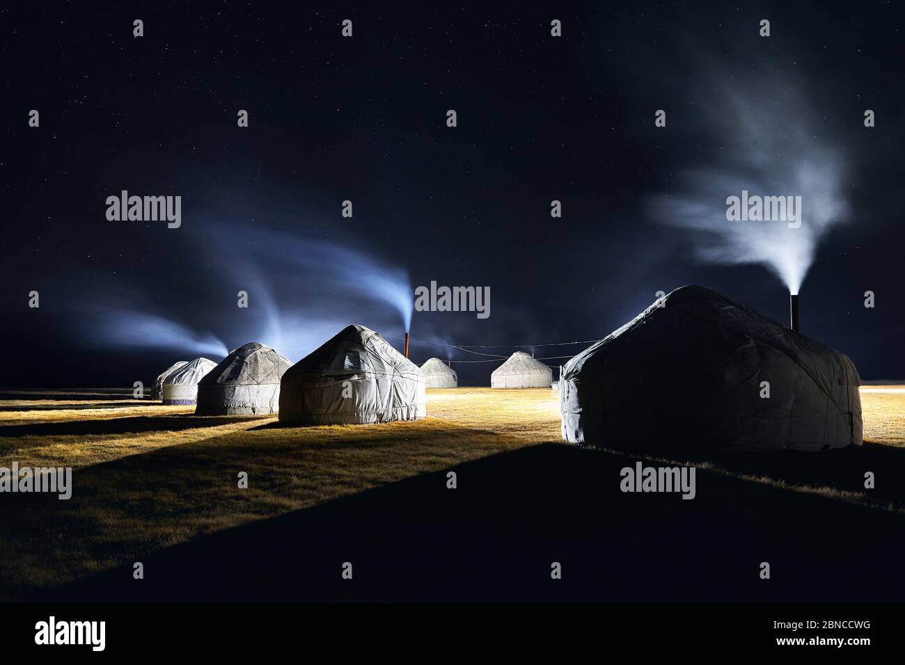 Yurt nomadic houses camp with smoke from the chimney at night sky with stars in Central Asia Stock Photo