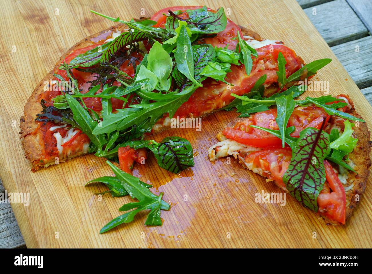 A pizza with red sauce and fresh salad on a gluten-free cauliflower crust Stock Photo