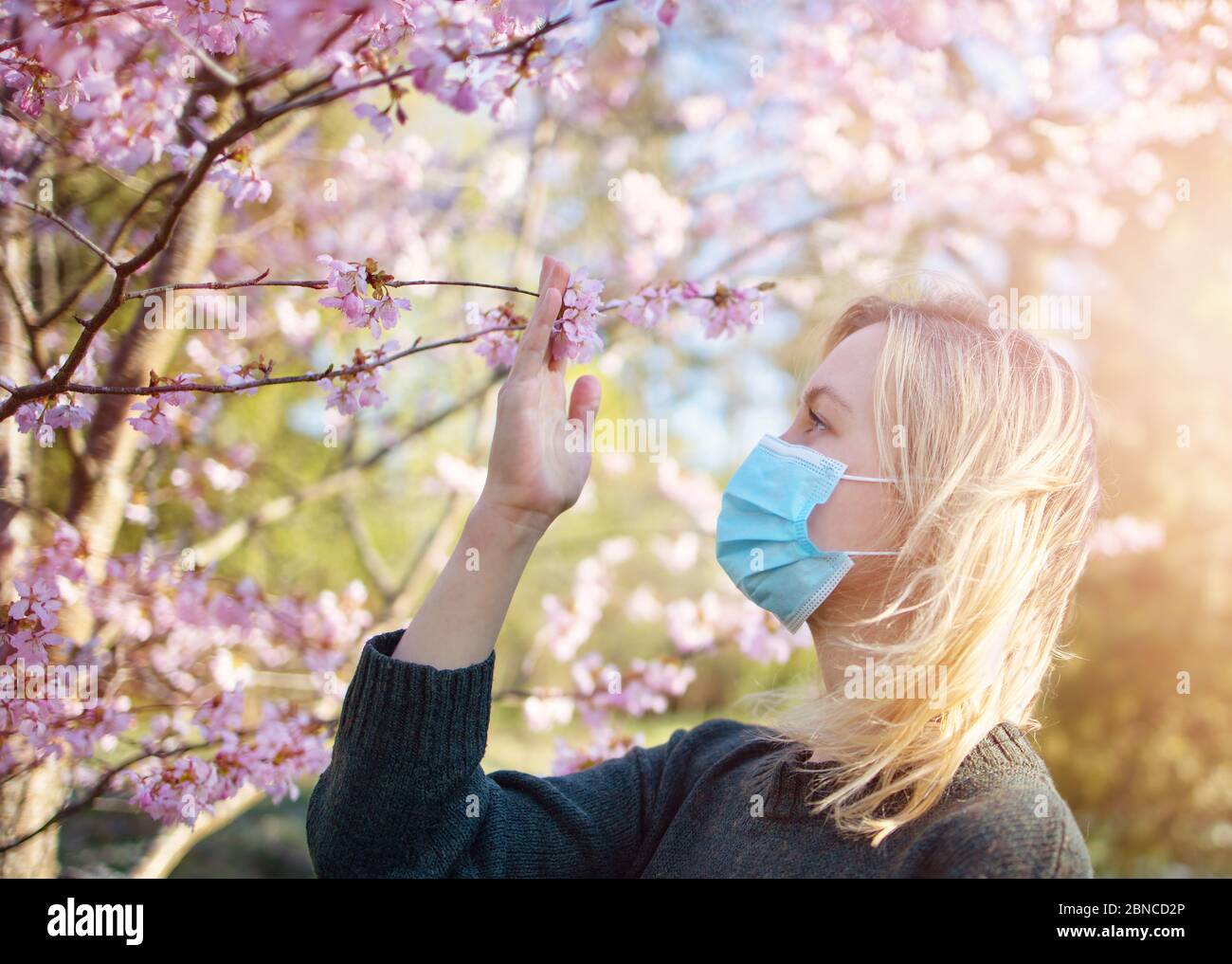 young woman in medical face protection mask outdoors in nature Stock Photo