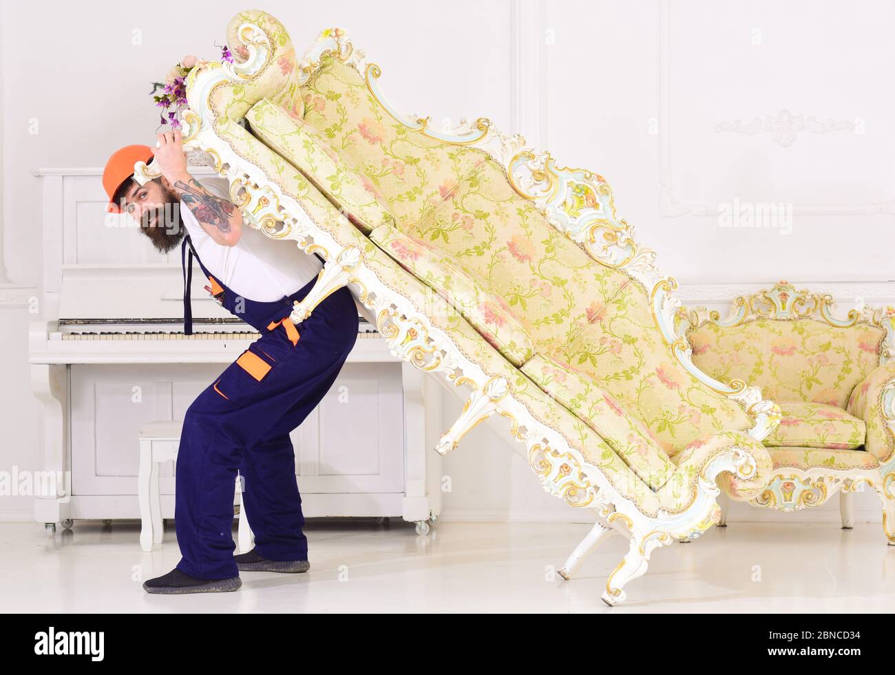 Delivery service concept. Loader moves sofa, couch. Man with beard