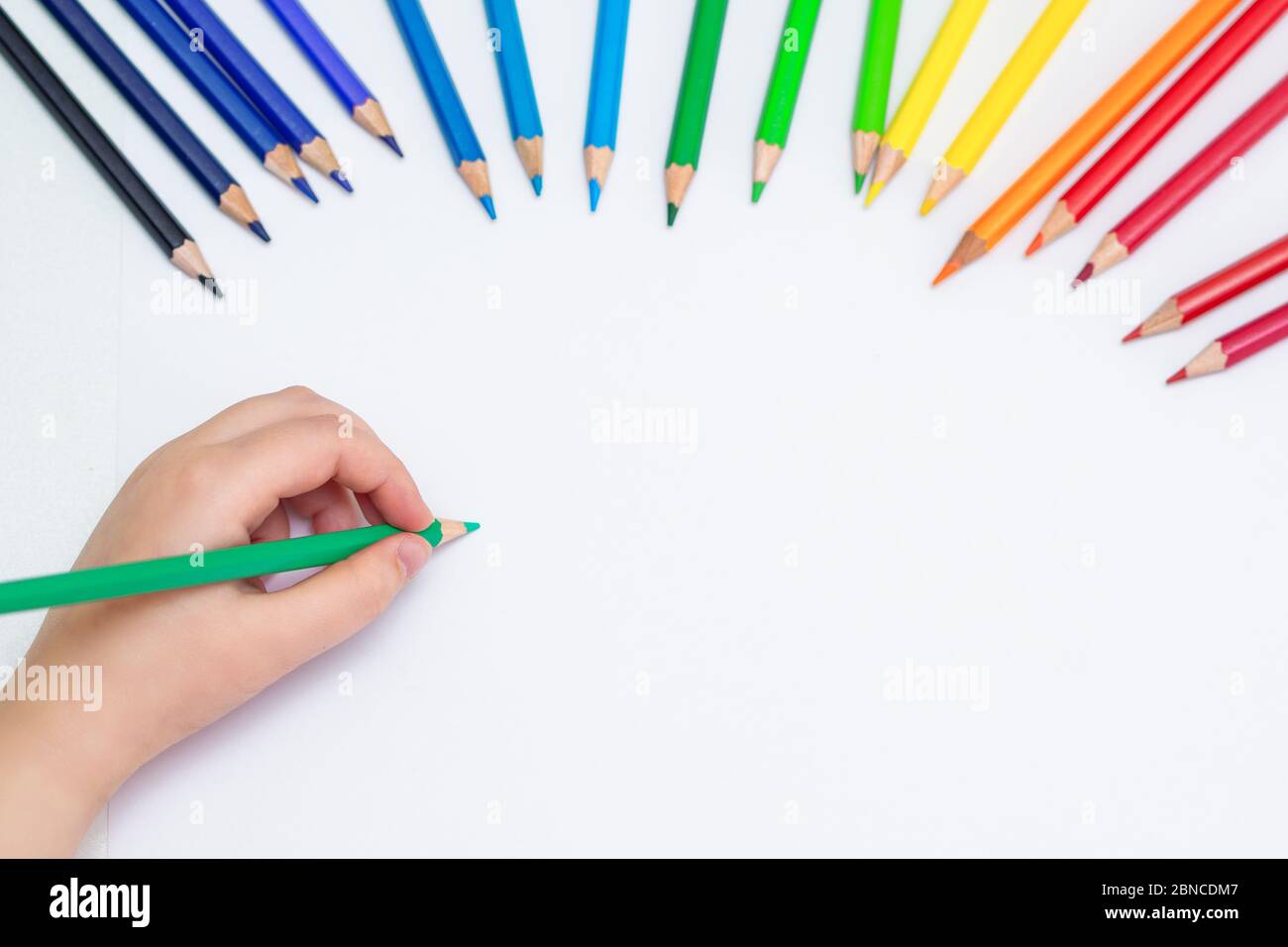 Top view of baby's hand drawing with green pencil on white paper with the  set of colour pencils. Kids painting concept. Copy space for text. Mockup  Stock Photo - Alamy