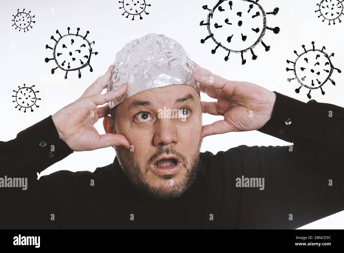 paranoid man wearing tin foil hat as protection against corona virus covid-19 - conspiracy theaory Stock Photo