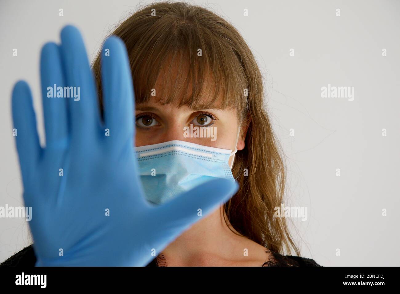 Covid-10 prevention and social distancing.  Young woman wearing mask and latex gloves taking preventative measures. Stock Photo