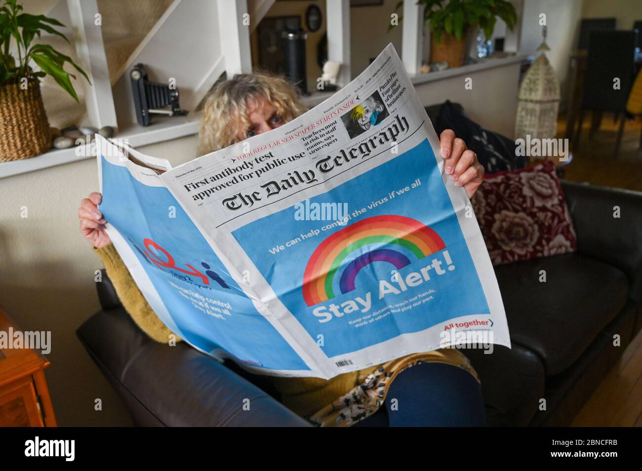 Brighton UK 14th May 2020 - A Brighton resident reads the Daily Telegraph which carries the governments 'Stay Alert' campaign message on the front page after lockdown measures had been relaxed slightly in England from yesterday during Coronavirus COVID-19 pandemic crisis  . Credit: Simon Dack / Alamy Live News Stock Photo
