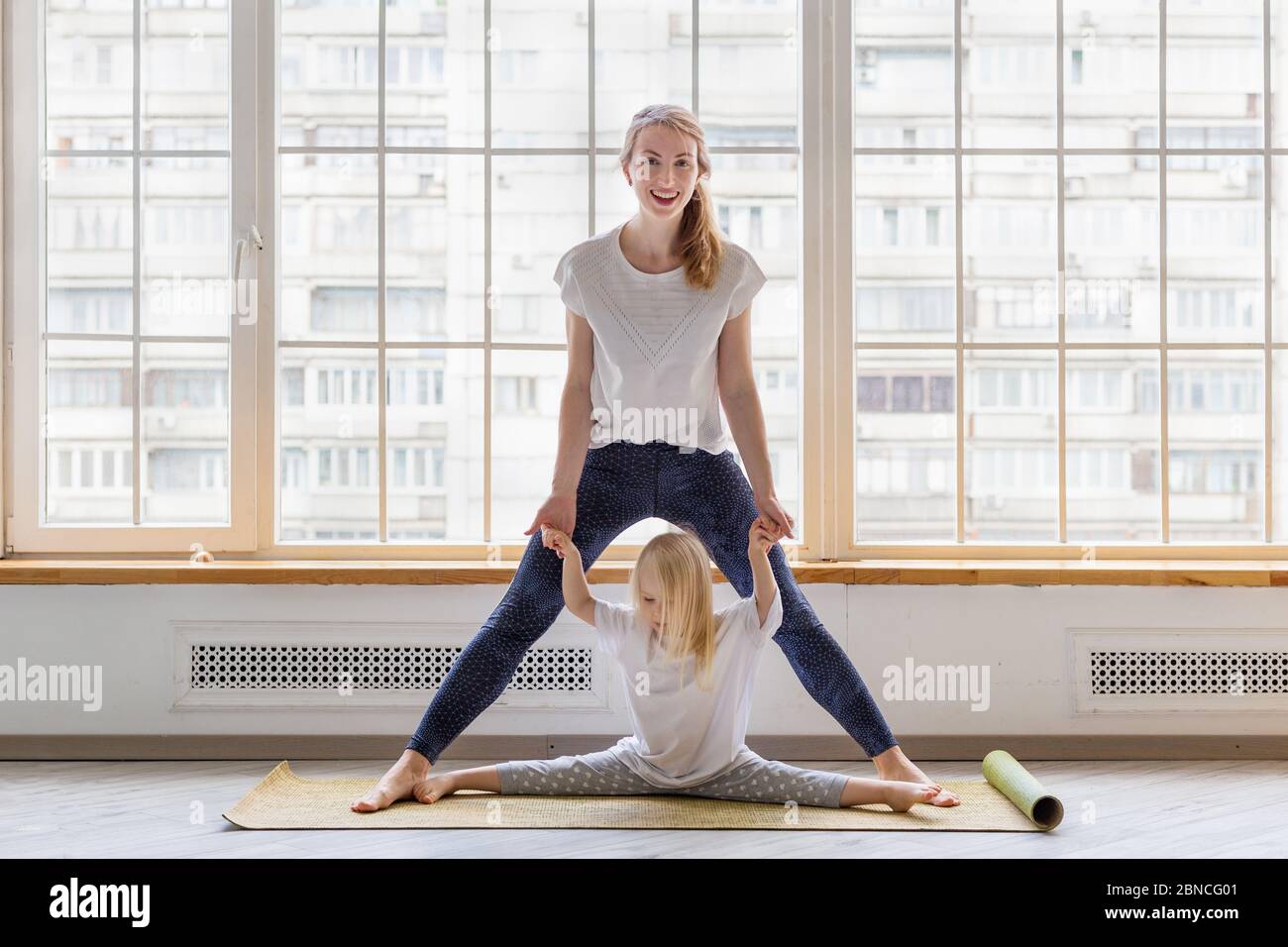 Young mother doing some stretching exercises with her daughter Stock Photo