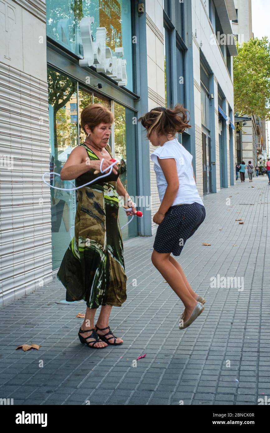 A young child enjoys skippig with her mothers help (Barcelona, Spain) Stock Photo
