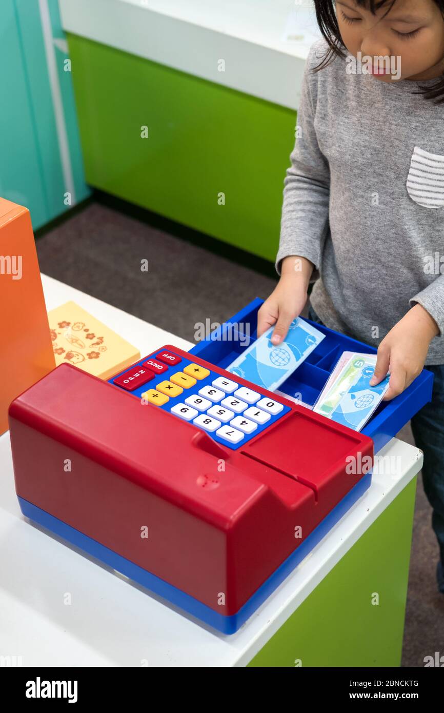 Cute Asian child, kid role playing Toy Supermarket cashier at indoor
