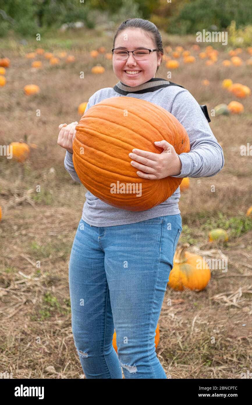 A girl carrying a large pumpkin at a farm Stock Photo