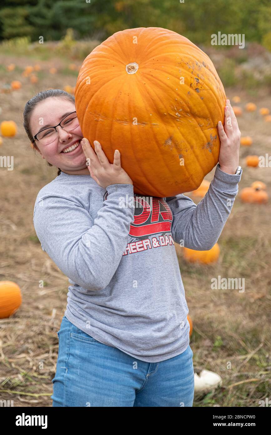 A girl carrying a large pumpkin at a farm Stock Photo - Alamy