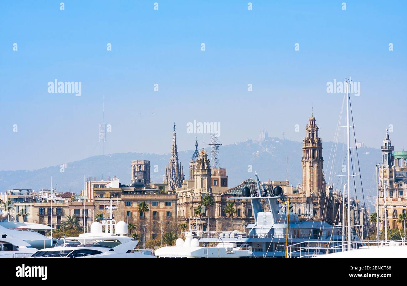 Barcelona, Spain - February 22, 2020: Luxury white modern yachts against old famouse buildings and mountains in port. Barcelona, Catalonia in sunny da Stock Photo