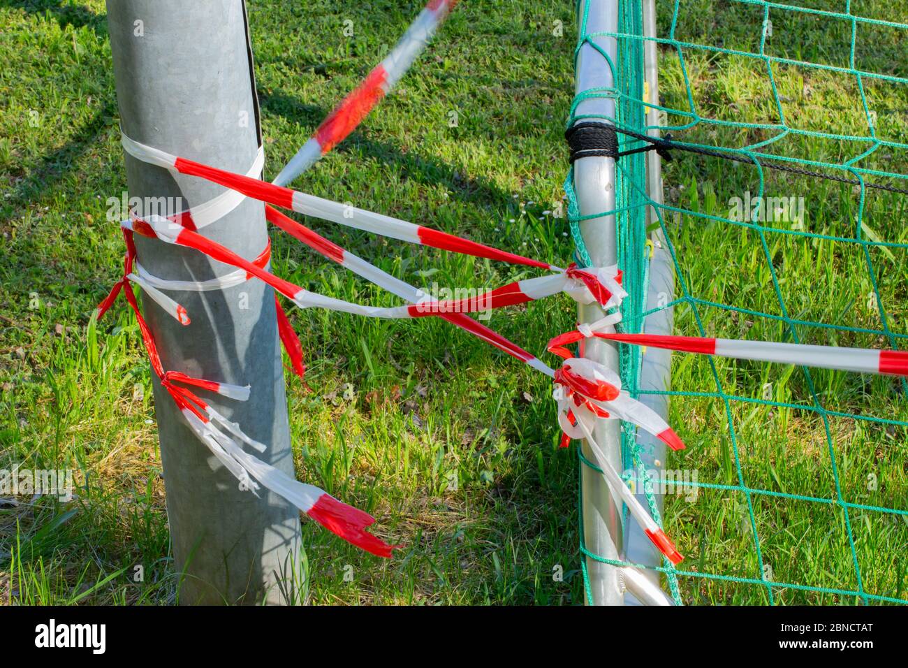 Red and white barrier tape tied to a soccer goal and a metal post