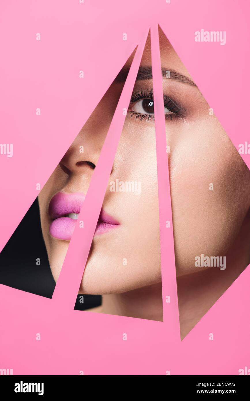 Girl with smoky eyes and pink lips looking across triangular holes in ...