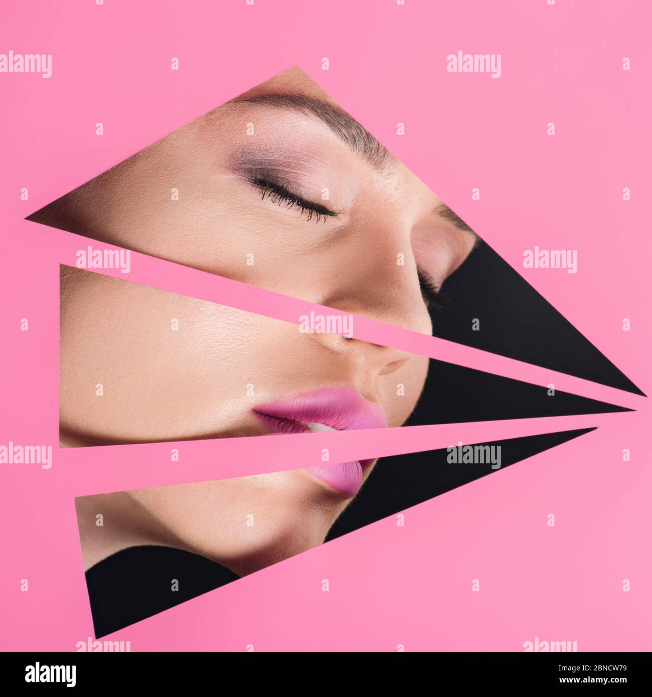 Female face with pink lips and closed eyes across holes in paper on ...