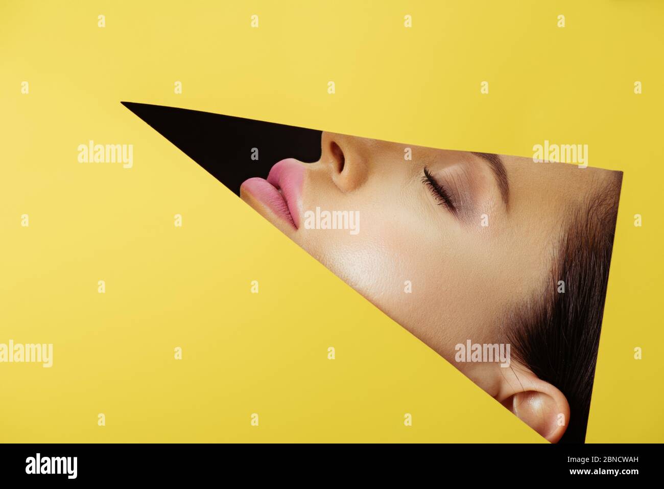 Female face with with pink lips and closed eyes in triangular hole in ...