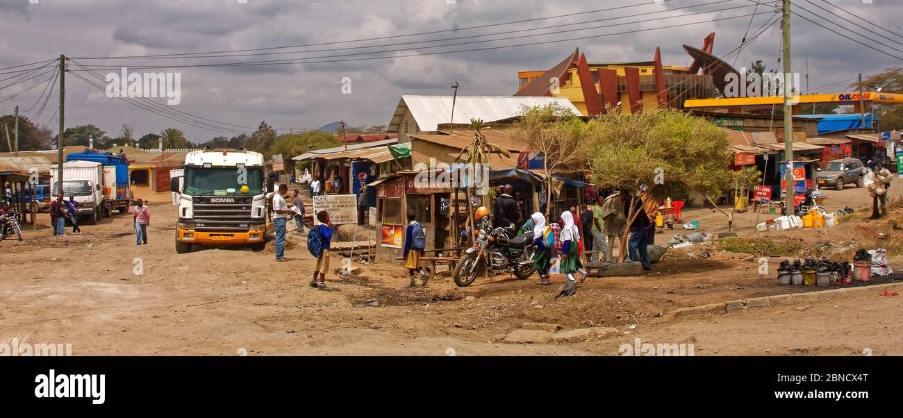 street scene, small shops, people, vehicles, dirt street, Cultural Heritage building beyond, Africa; Arusha; Tanzania Stock Photo