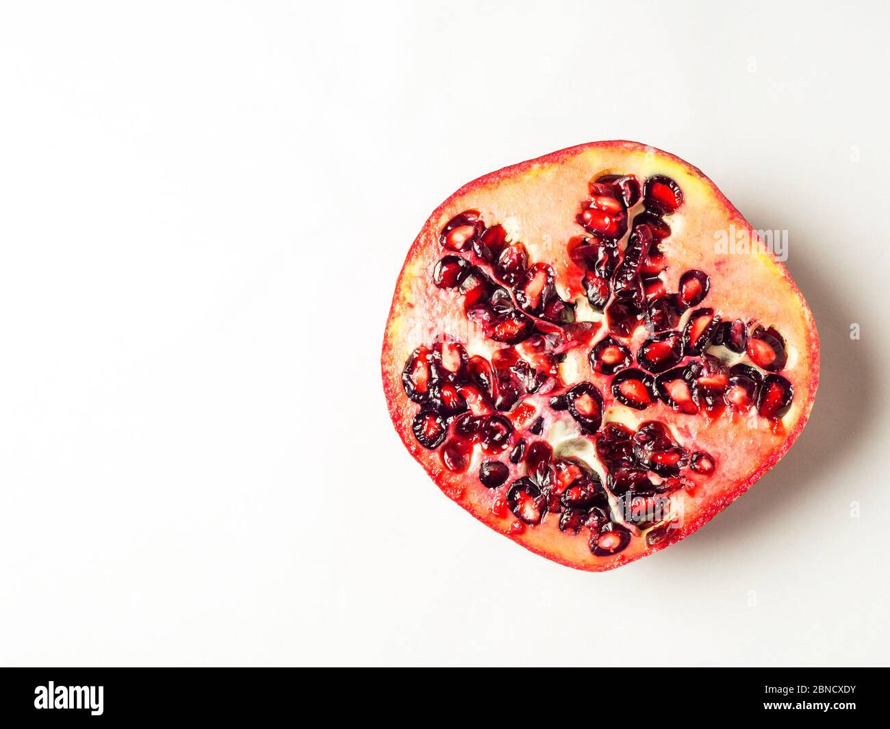 Half a fresh pomegranate on a white background with copy space Stock Photo