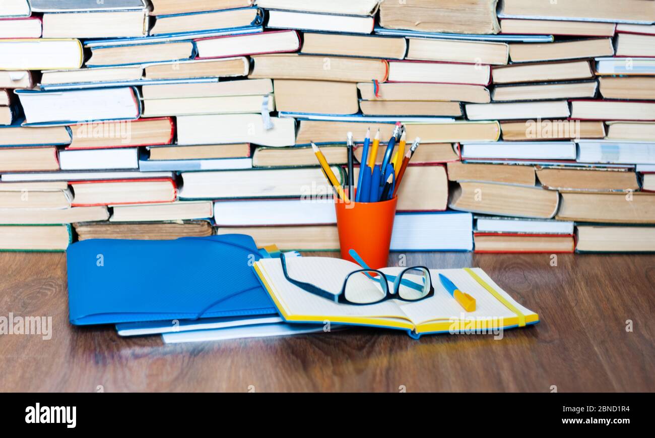 Open textbook, notebook, glasses, pencils in holder, plastic folder ...