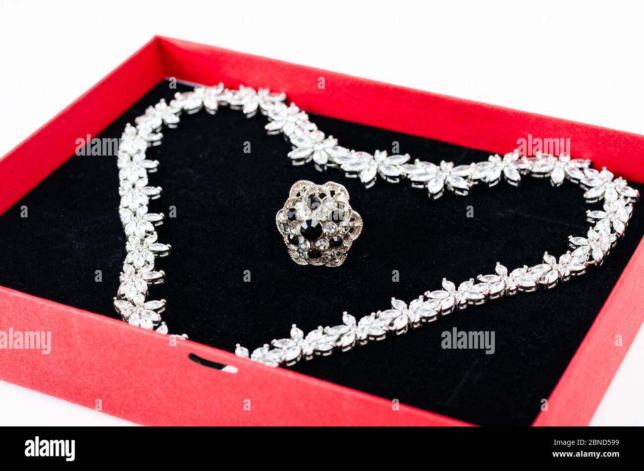 Close-up of white gold chain and gemstone ring in gift box ready for valentine's day gift on white background . Stock Photo