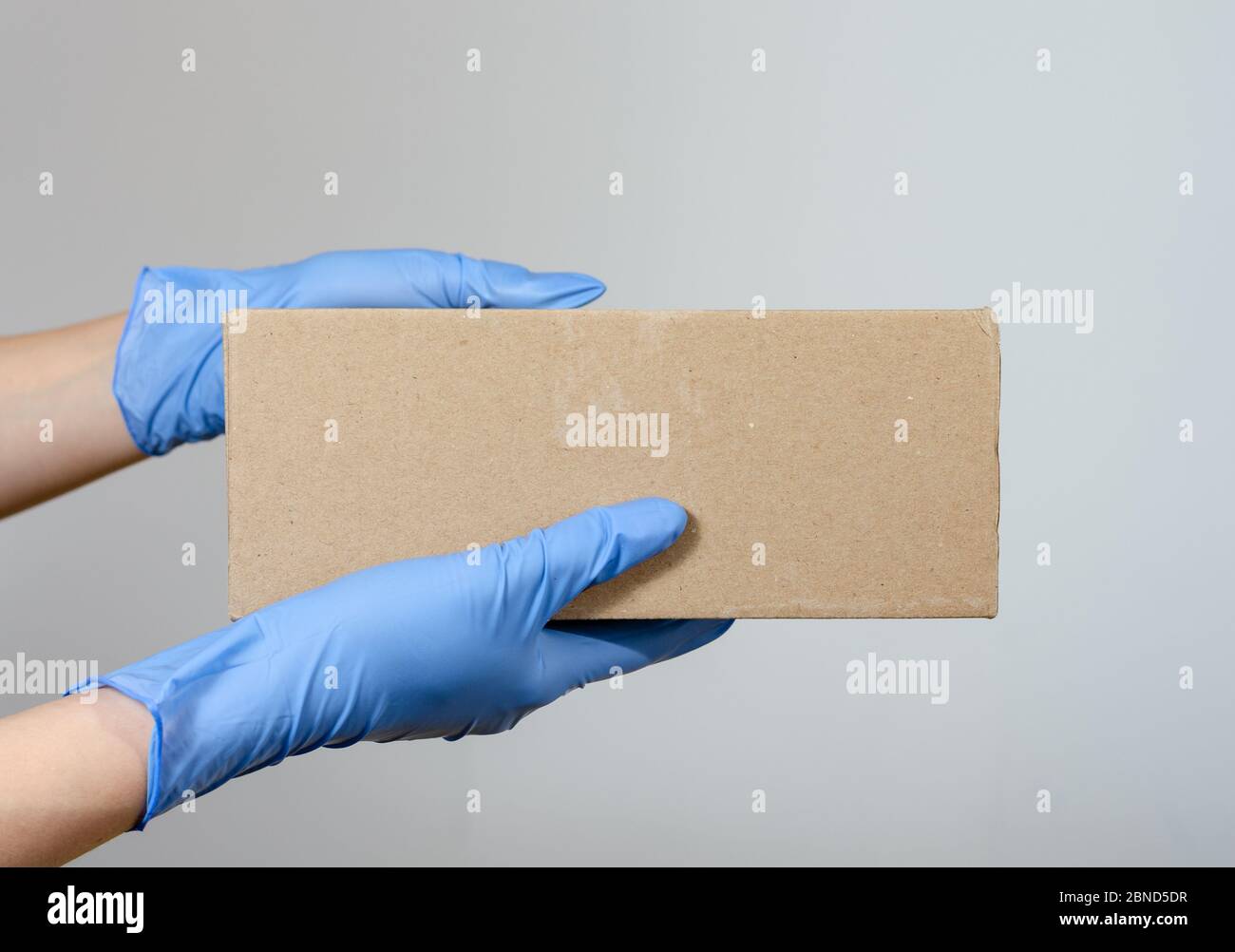 Hands with surgical gloves of a woman or man holding a cardboard ...