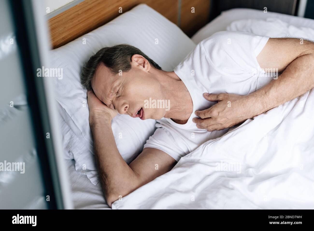 https://c8.alamy.com/comp/2BND7WH/overhead-view-of-sick-man-coughing-while-lying-on-bed-2BND7WH.jpg