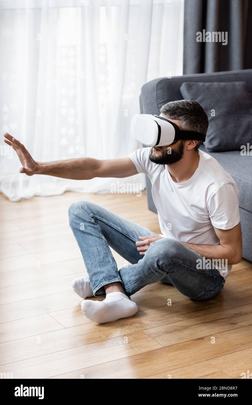 Man using virtual reality headset while sitting of floor at home Stock ...