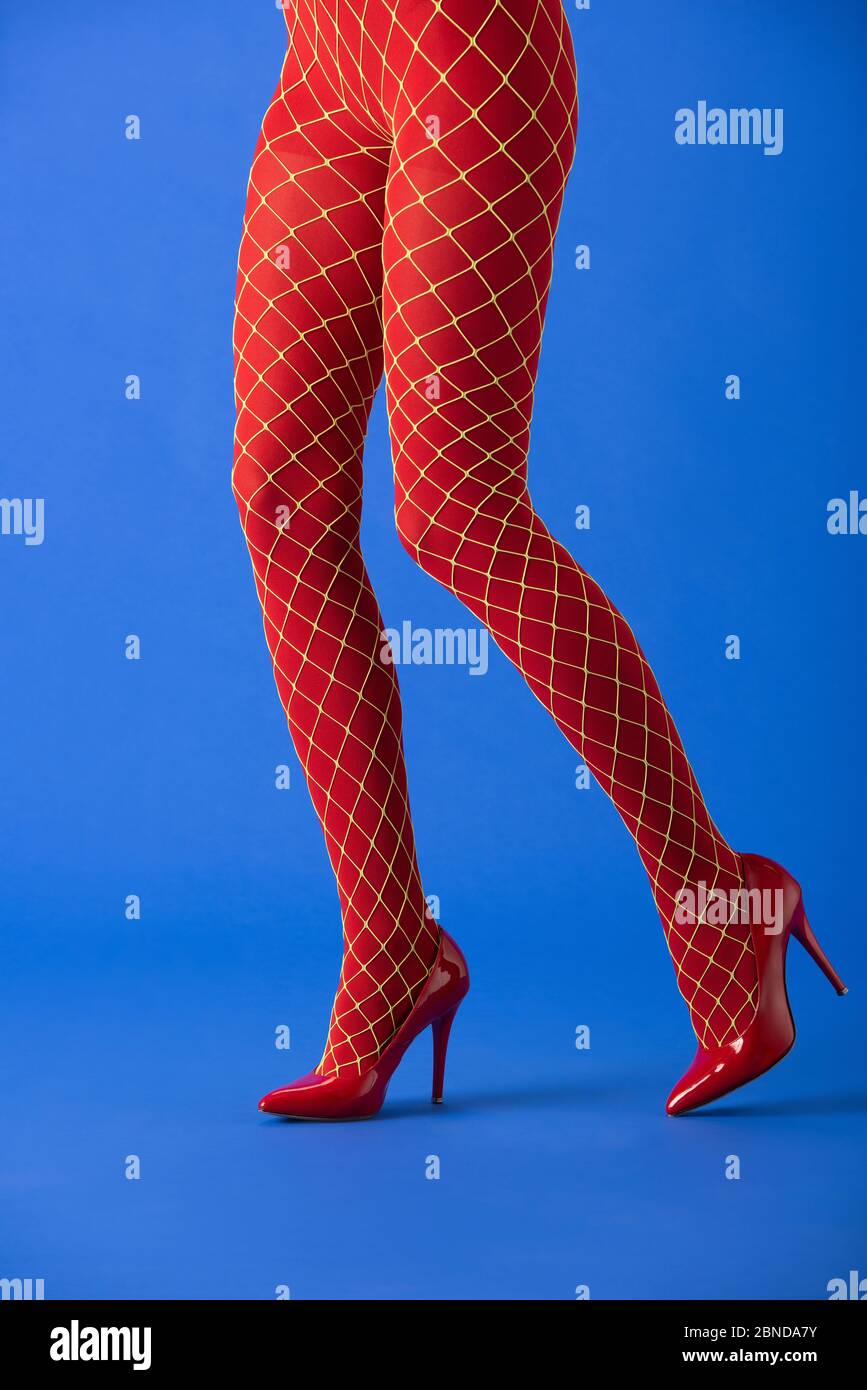 cropped view of model in fishnet tights and red heels posing on