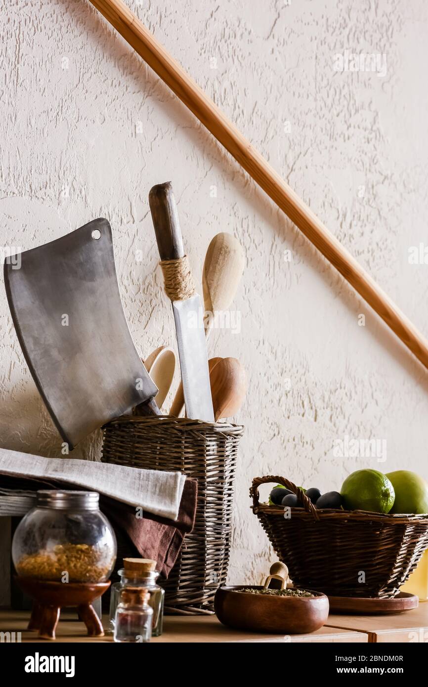 wooden spoons and knifes near juicy fruits, herbs and spice in bottles