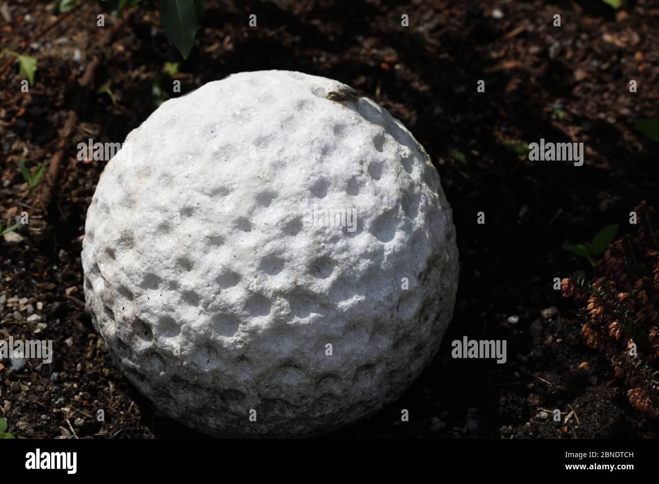 steinerner golfball in der Erde als Symbol für den Riefensberger Golflatz Stock Photo