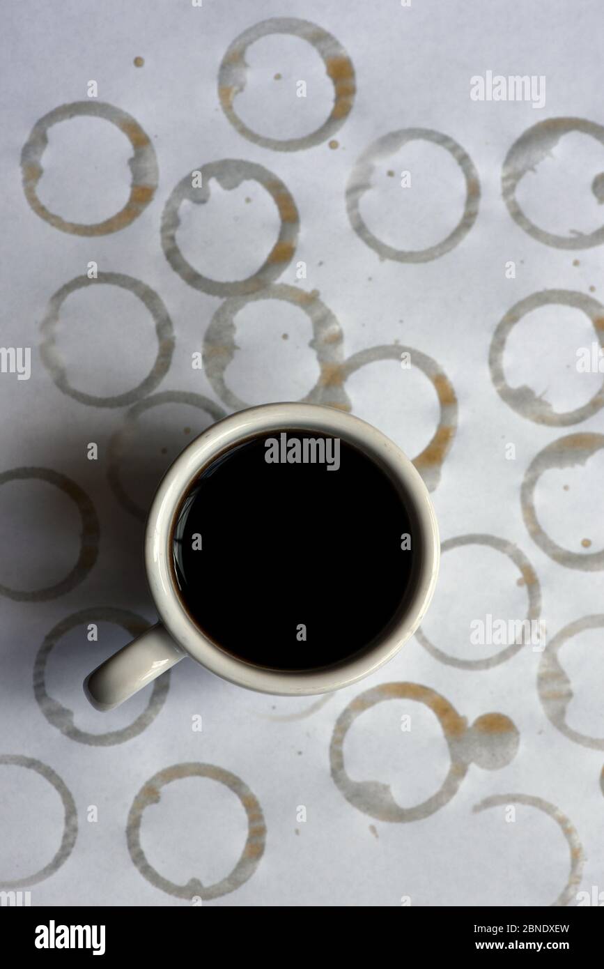 A white cup of black coffee sits on a white paper tablecloth background
