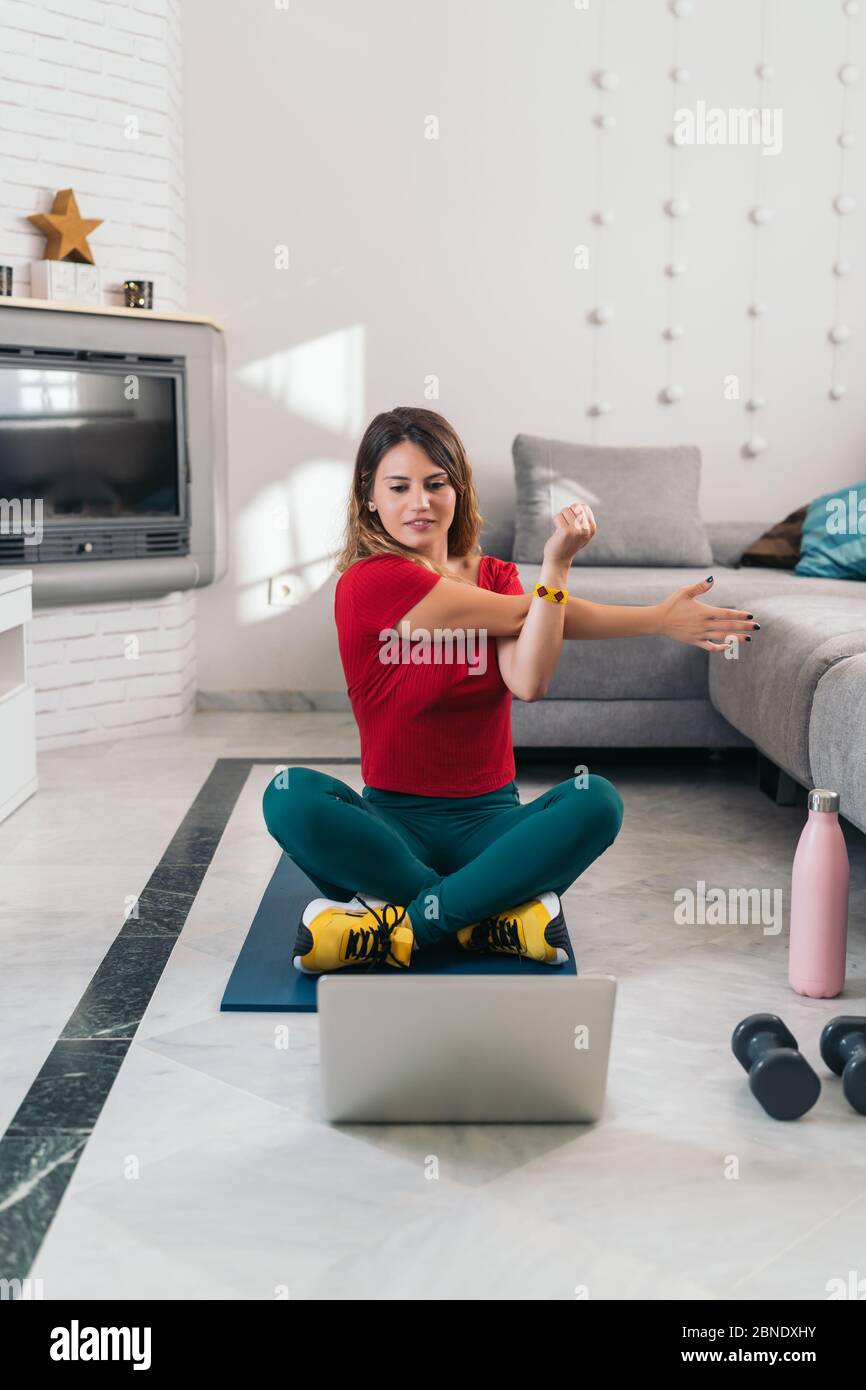 woman doing sports on a mat following online classes with laptop at home Stock Photo