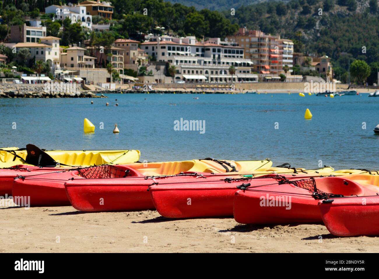 Red kayaks lined up on the beach in Port de Soller, Majorca, ready to be taken out by adventurous visitors Stock Photo
