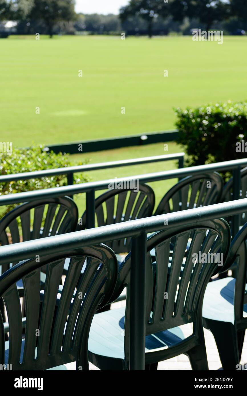 Empty front row seats overlooking a playing field on a sunny day Stock Photo