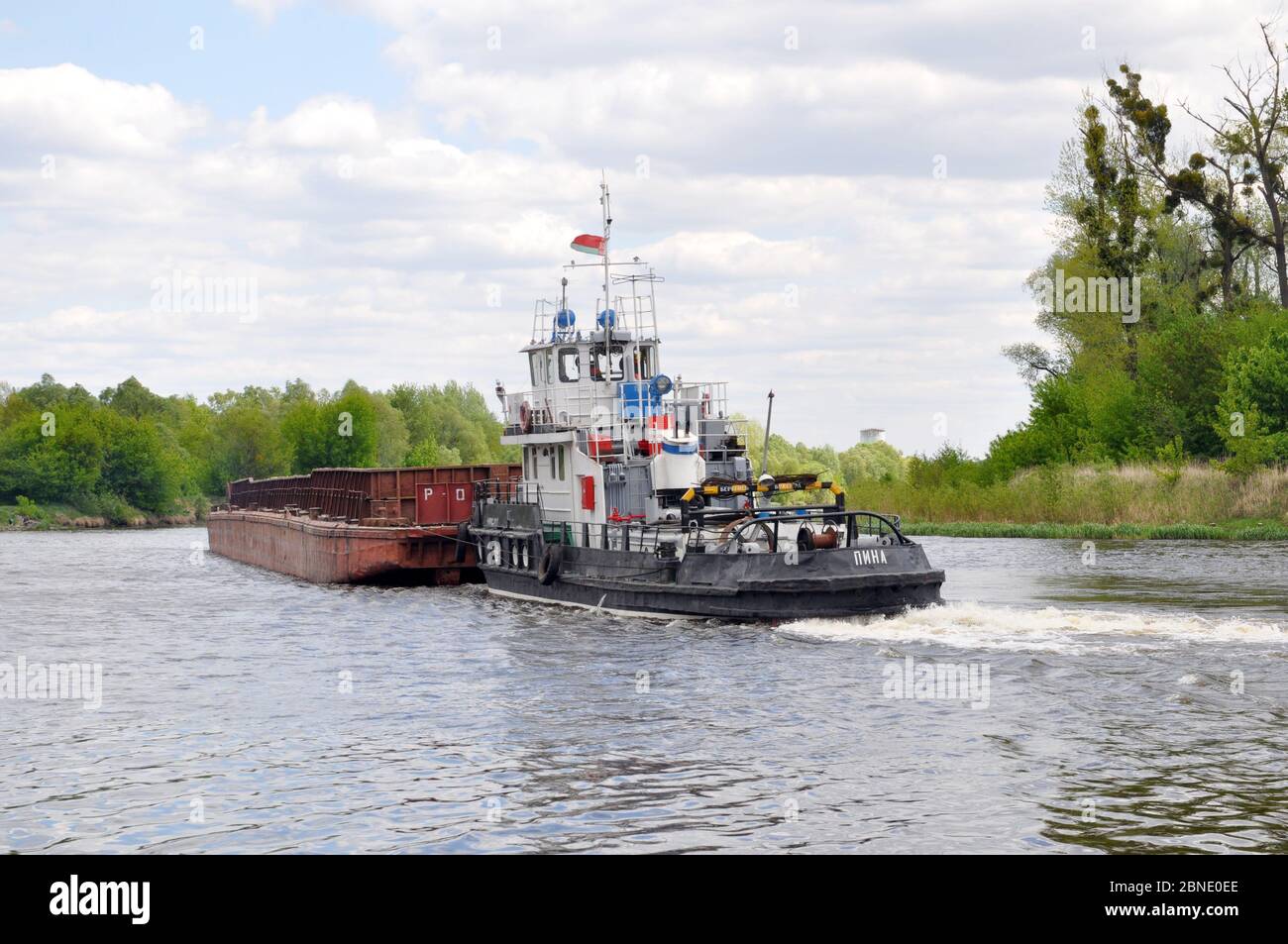 Movement of a tugboat with a barge along the Pripyat River. Stock Photo