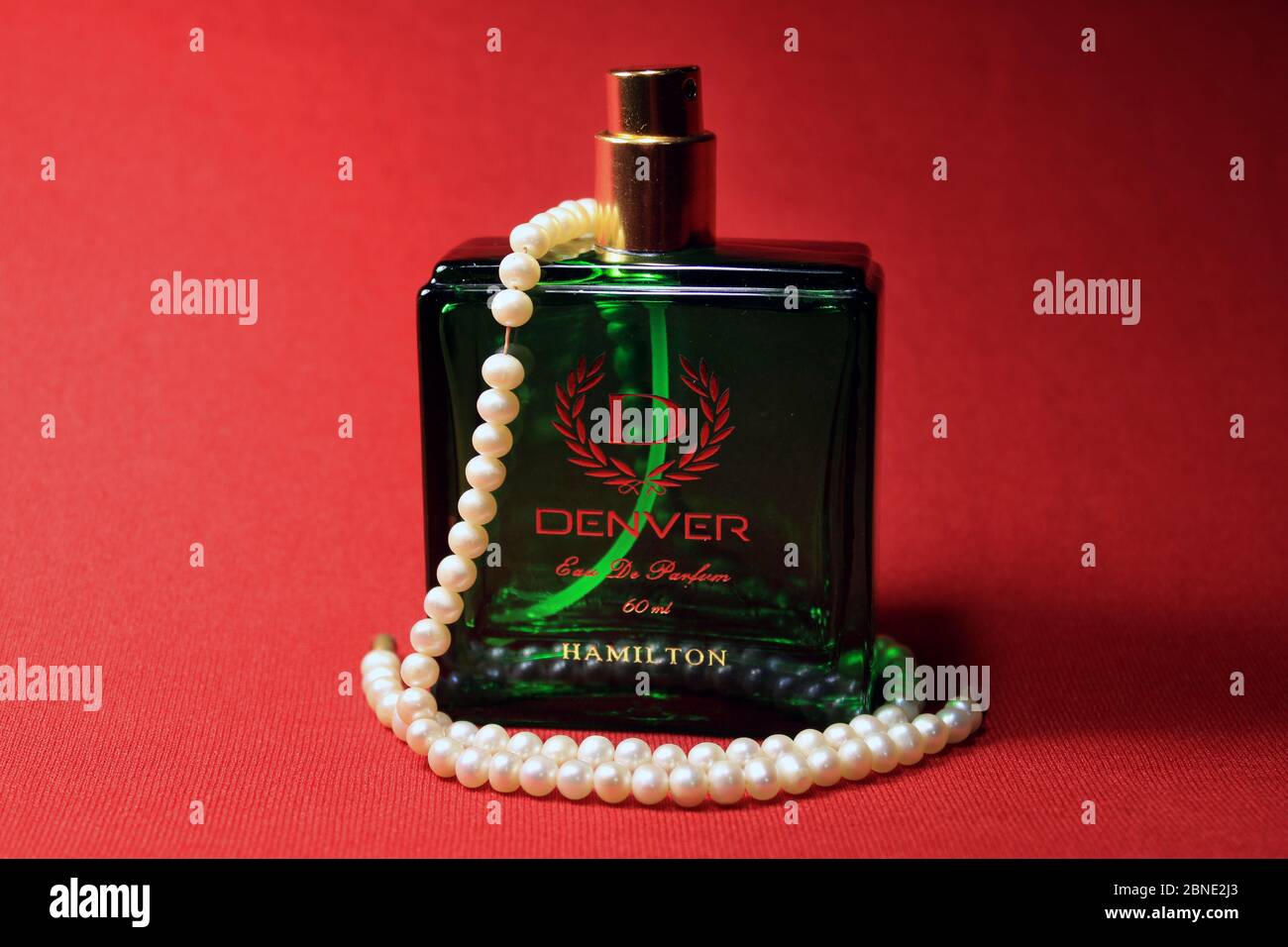 Green color perfume bottle isolated on red background. Denver Hamilton  Perfume For Men Stock Photo - Alamy