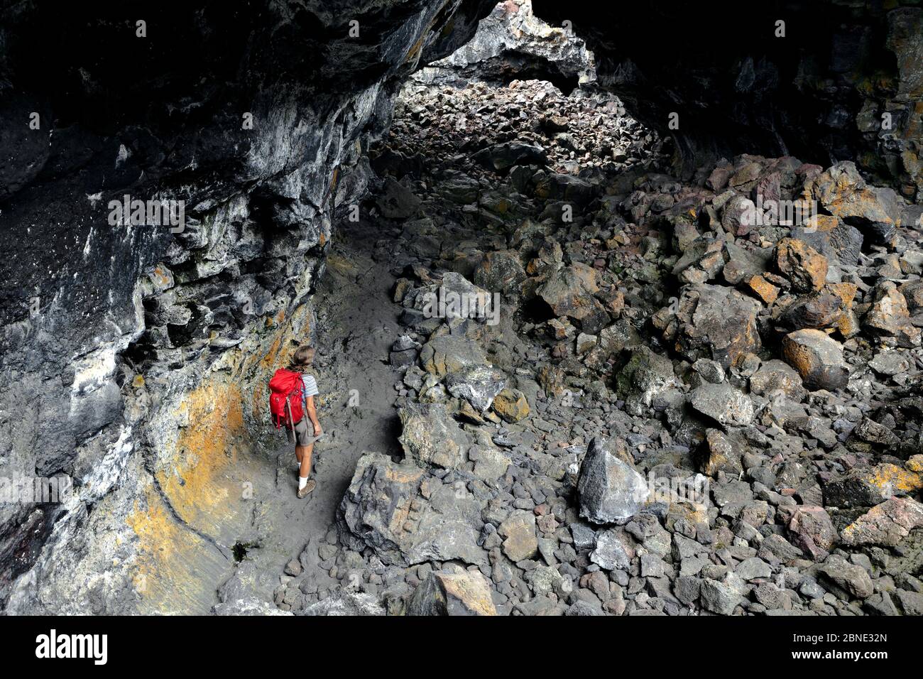 Hiker walking through Indian Tunnel in Craters Of The Moon National Monument, Idaho, USA, July 2015. Model released. Stock Photo