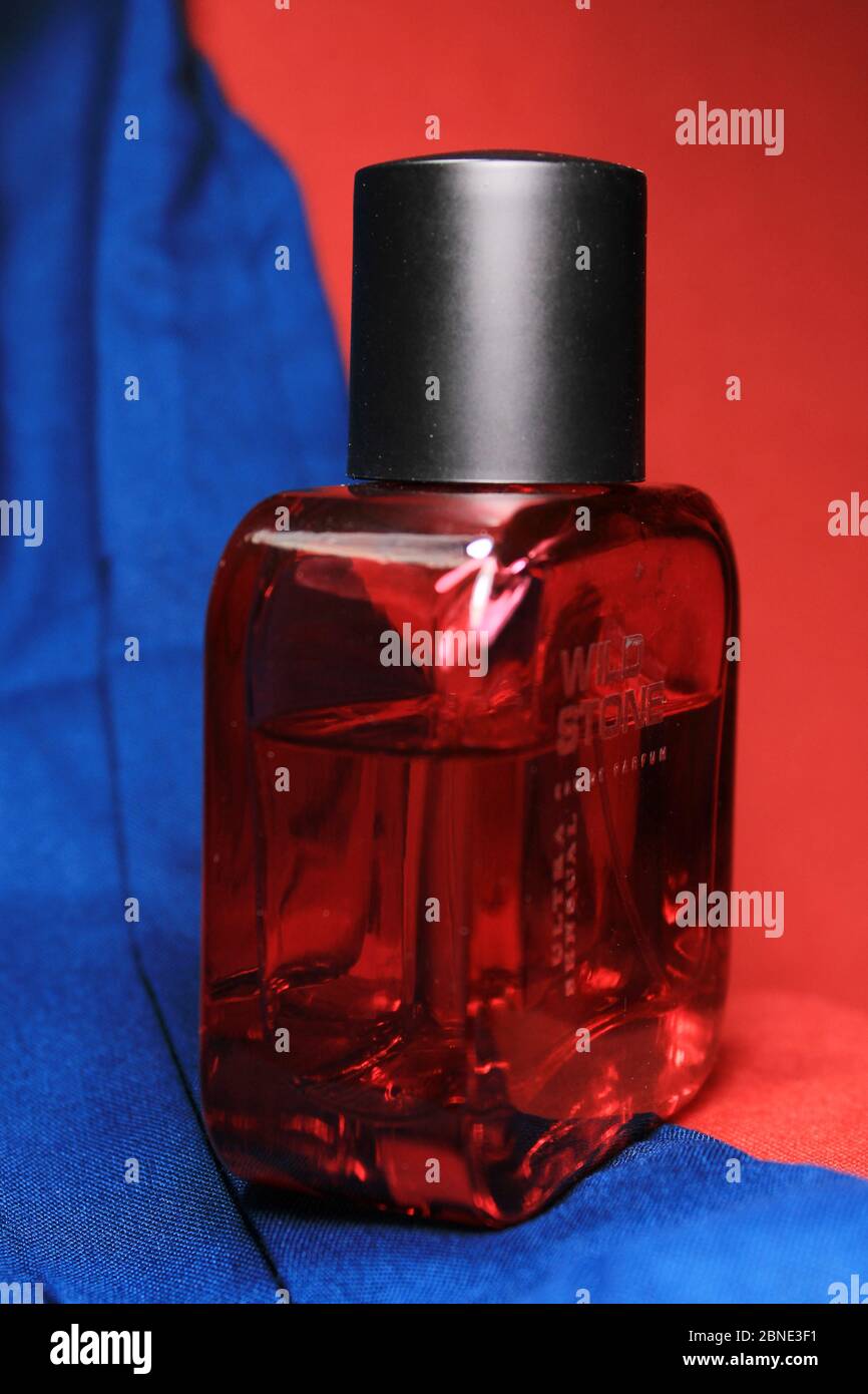 Red color men perfume bottle isolated on blue and red background with ...