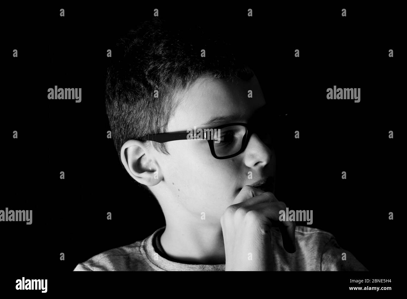 Boy with glasses looks thoughtfully in portrait Stock Photo