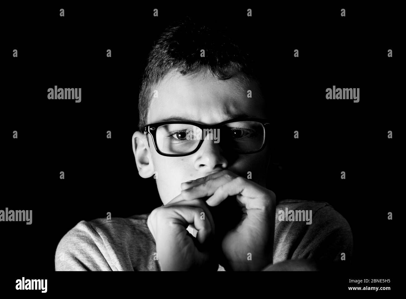 Boy with glasses looks lonely into the camera Stock Photo