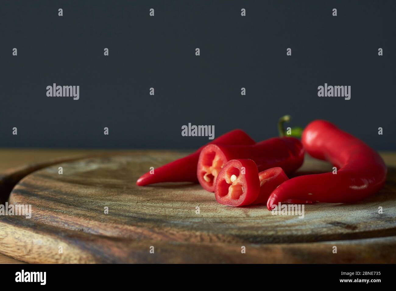 Close up of sliced red hot chili peppers on wooden cutting board ...