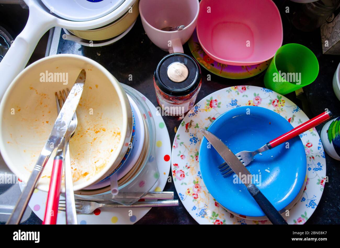 Washing up - Plates, dishes, knives, forks, cups stacked on a kitchen worktop ready to be cleaned. Stock Photo