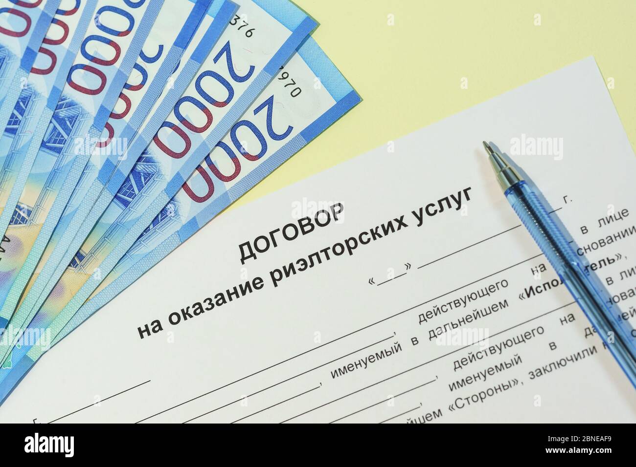 Registration of an agreement on a transaction with property. Russian text "Contract for the provision of realtor services", ruble bills for payment an Stock Photo