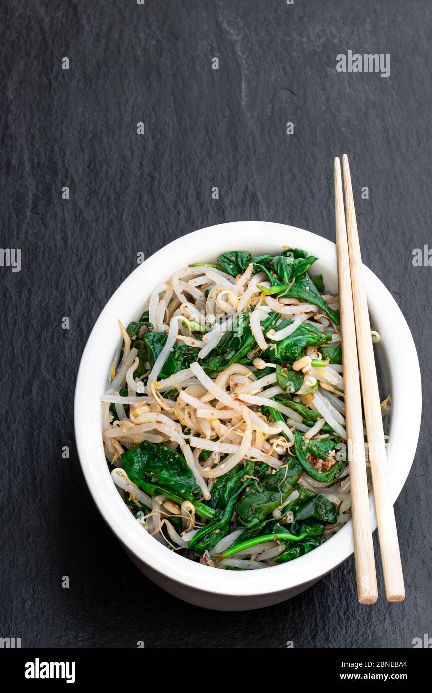Korean spinach mung bean sprouts salad on black stone background Stock