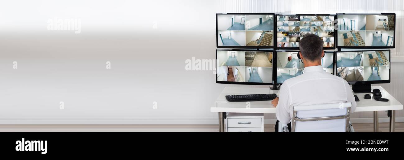 Security System Operator Looking At CCTV Camera Footage On Computer ...