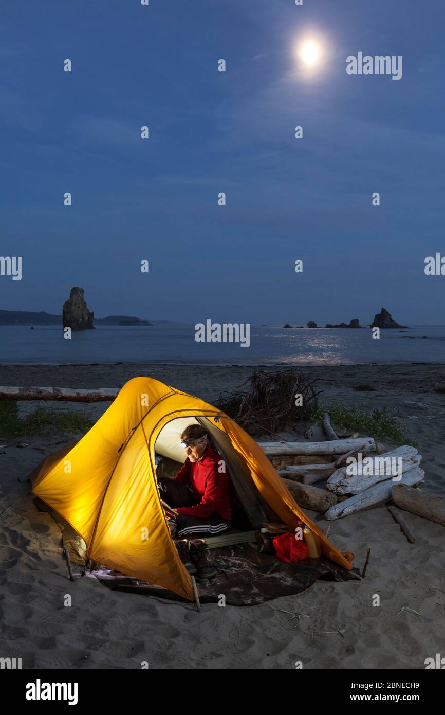 Moon rising over campsite, Toleak Point, Olympic National Park, Washington, USA. August 2015. Model released. Stock Photo