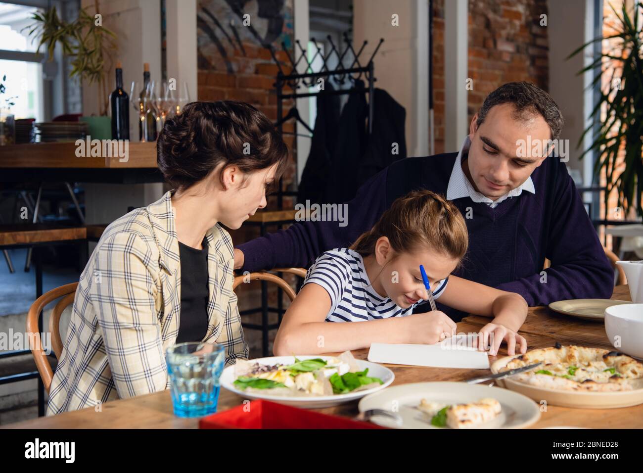 Young parents checking their daughter's homework. There are a few ...